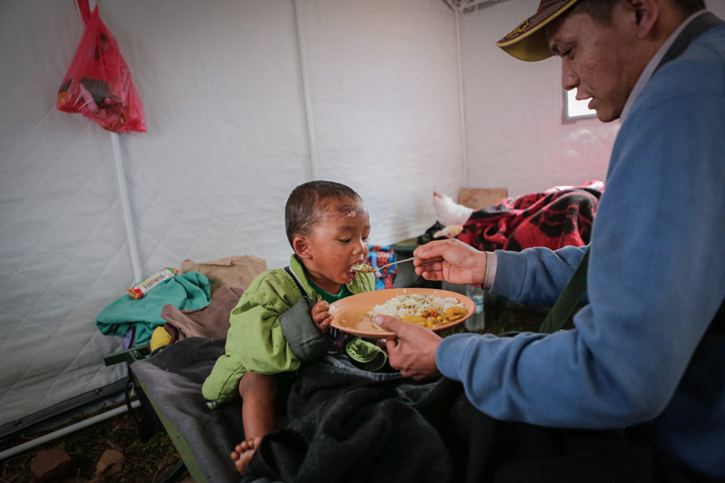Young boy being fed at relief camp after Nepal earthquake
