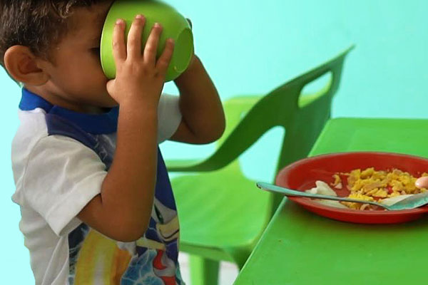 Enfant savourant un repas nutritif dans un espace SOS adapté aux enfants.