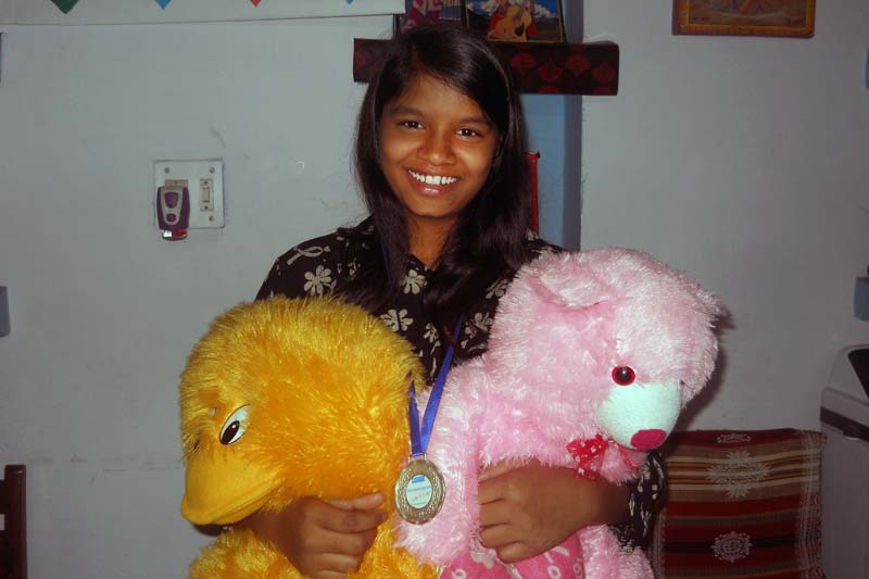 Girl with medal and teddy bears in India