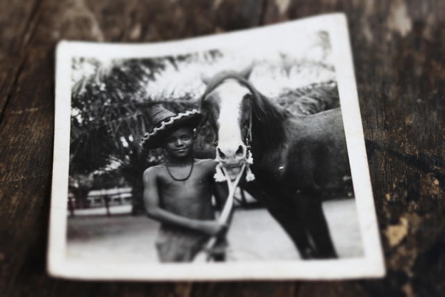 Photo en noir et blanc de Raphaël Adou enfant, debout à côté d'un cheval.