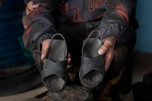 Secundino montrant les chaussures personnalisées qu'il produit.