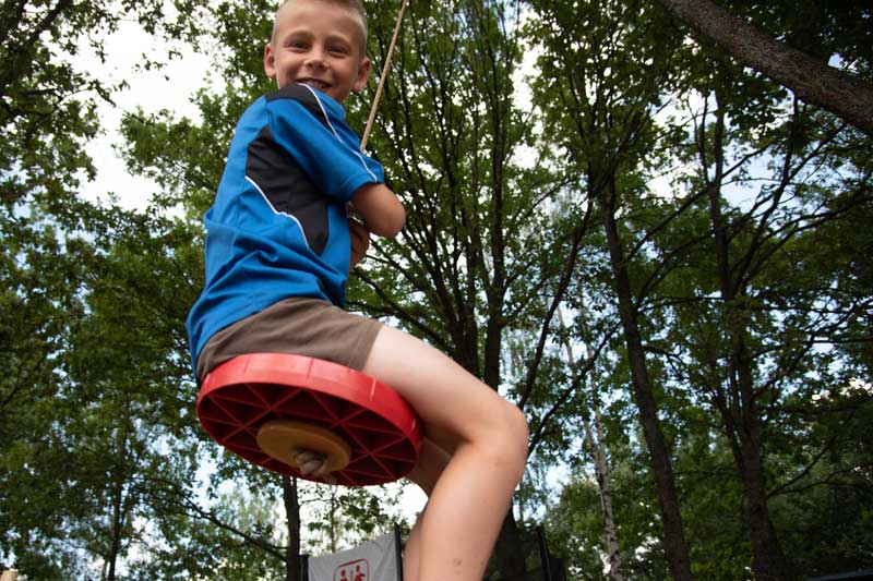 Smiling boy on swing au camp d'été en Biélorussie