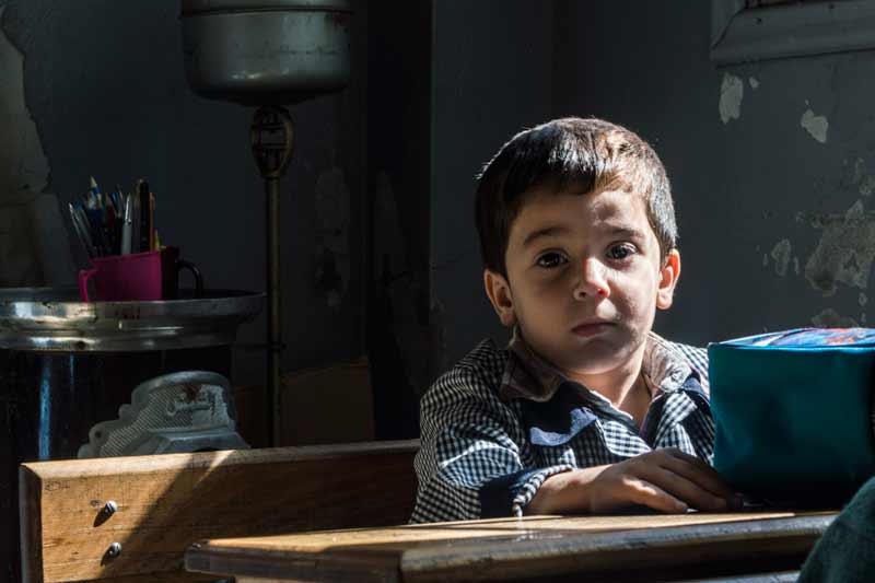 Enfant syrien assis à son bureau dans une salle de classe