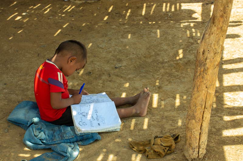 Boy sitting on ground with notebook, SOS emergency response program in Colombia