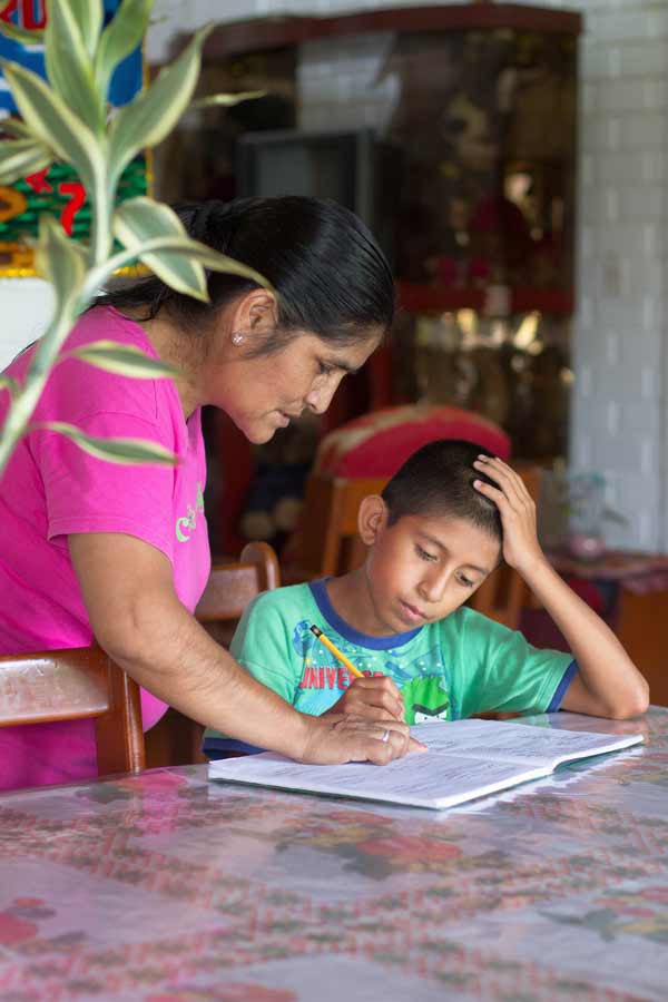 Child doing homework while being helped by their SOS mother