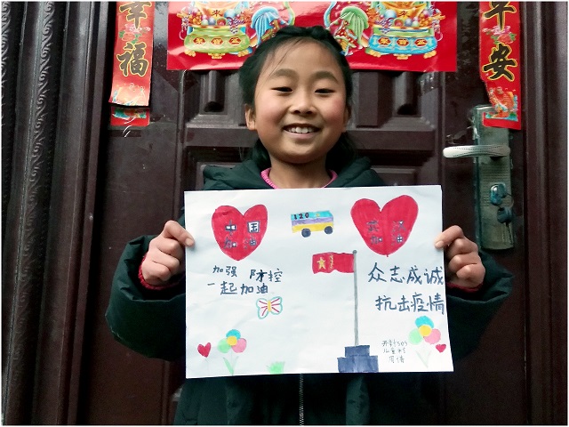 An SOS child shows off a homemade newspaper about the coronavirus outbreak.