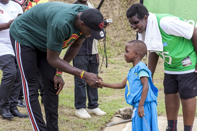 Le "géant" Pascal Siakam serre la main d'un jeune enfant SOS.