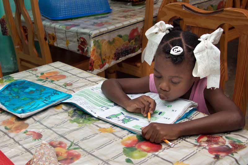 Enfant parrainé faisant ses devoirs scolaires aux Cayes, Haïti