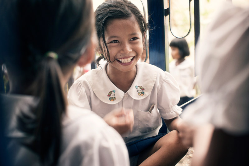 SOS sponsored child smiling while eating in Battambang, Cambodia