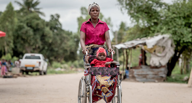 Leila, 5 ans, est dans le fauteuil roulant fourni par SOS Villages d'Enfants, poussée par sa grand-mère Chica.