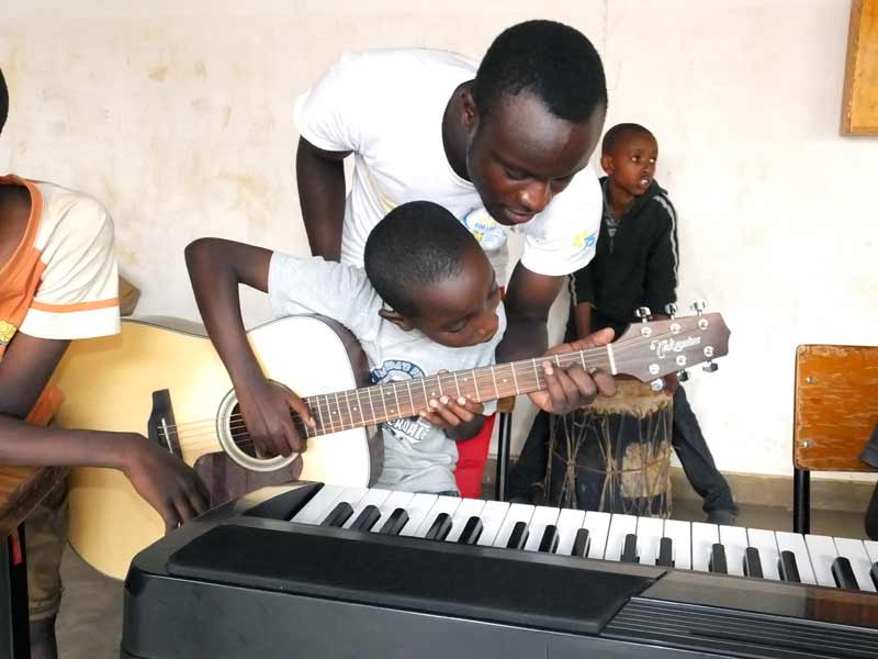 Aluda Euniver, the music teacher at SOS Children’s Villages in Buru Buru, Kenya shows a young student how to play the guitar.