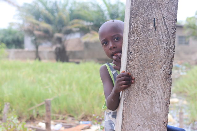 A shy SOS child hiding behind a column in Liberia