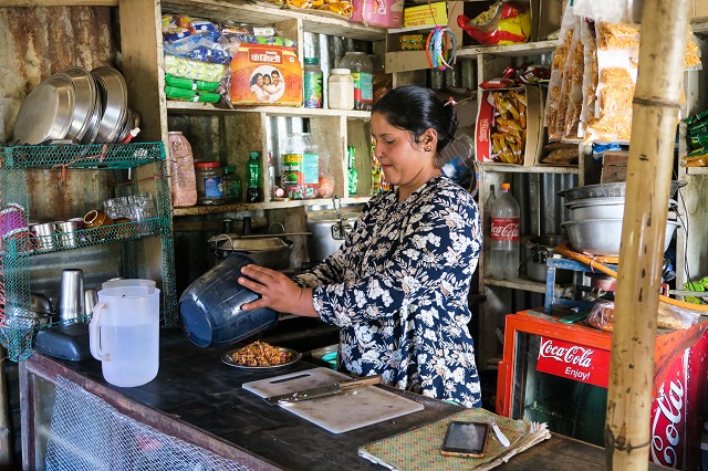 Sumitra prépare de la nourriture pour un client dans sa boutique.