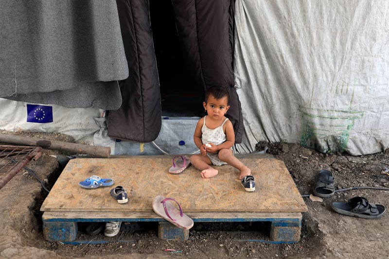 Boy sitting outside of a tent in the refugee camp in Lesvos, Greece Boy sitting outside of a tent in the refugee camp in Lesvos, Greece