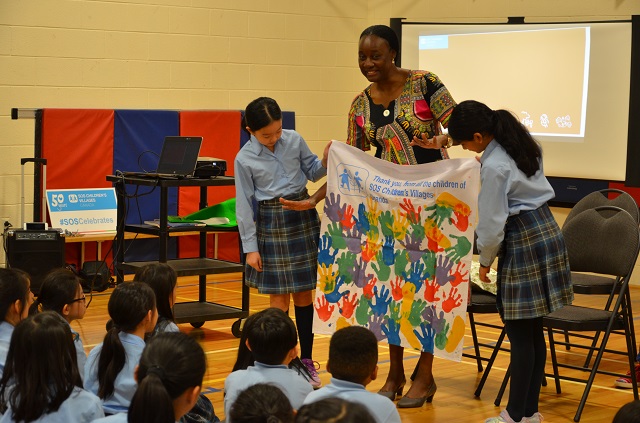 Olive Lumonya presenting a gift to students during her school visit.