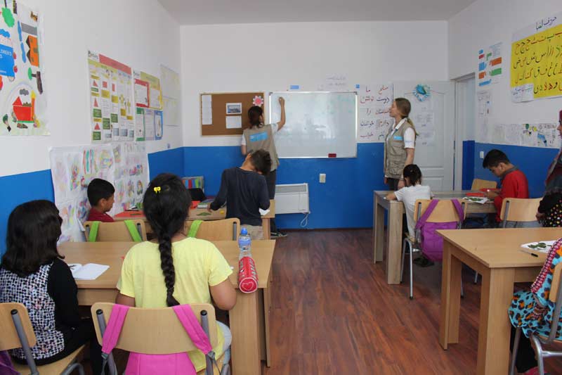 SOS Villages d'Enfants Serbie a créé une école improvisée au centre d'accueil de Preševo. L'éducatrice Jelena Zdravković écrit le sujet d'aujourd'hui sur le tableau blanc : Herbier.