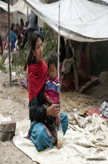 Mère et enfant assis sous une tente de fortune après le tremblement de terre au Népal