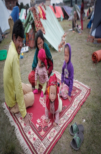 Nepalese family caring for children outside on carpet