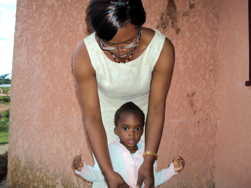 SOS mother adjusting child's clothing in Cameroon