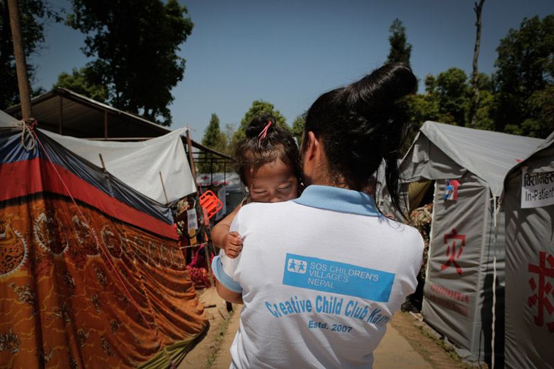 SOS Nepalese volunteer holding a child after 2015 earthquake