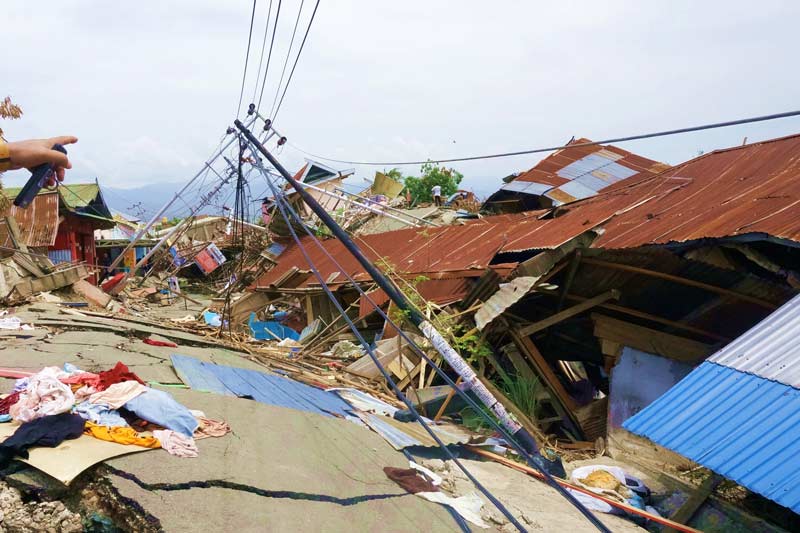 Rue et maisons endommagées par le tremblement de terre et le tsunami indonésiens