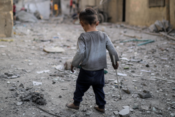 Boy in gaza walking through rubble
