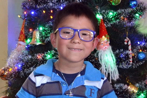 Marco* smiling in front of the Christmas tree