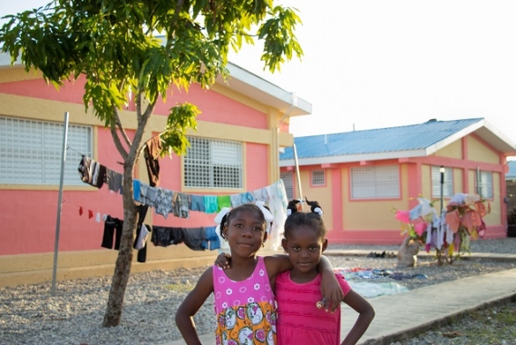Two smiling SOS children standing in front of their new SOS home.