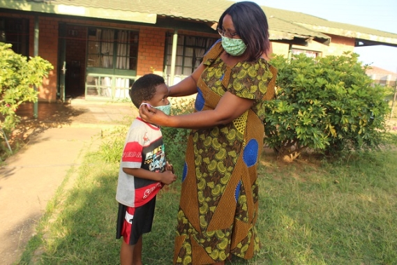 SOS mother Phoebe helps her youngest put on a protective mask