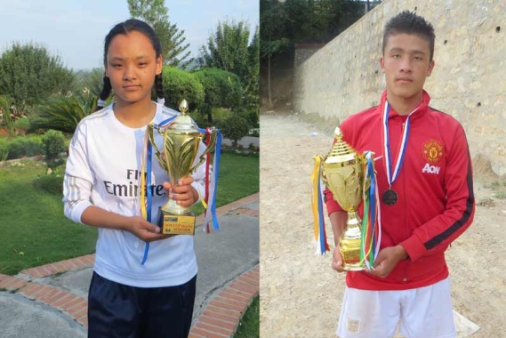 Nepalese girl and boy each with a soccer trophy