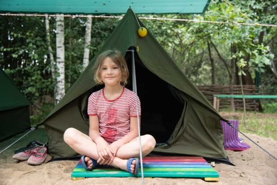 Girl sitting in front of tent at summer camp in Belarus