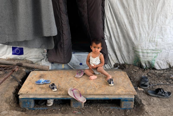 Boy sitting outside of a tent in the refugee camp in Lesvos, Greece