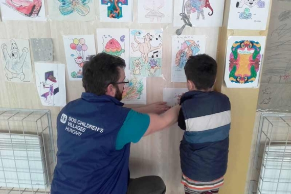 Refugee child putting up a picture
