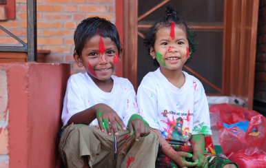 two young children in Nepal with paint on their hands, face and clothes