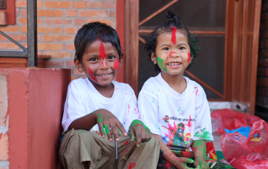 two young children in Nepal with paint on their hands, face and clothes