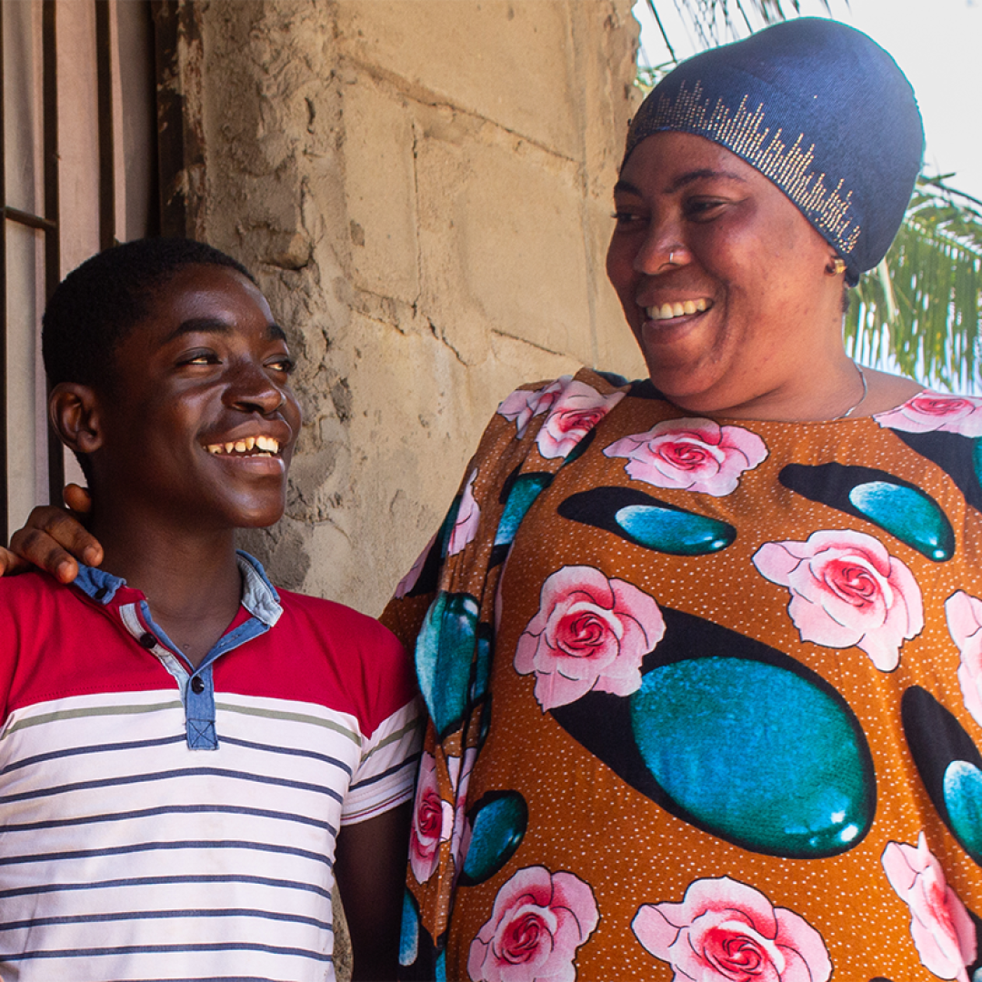 Kinship care, aunt and nephew smiling together outside their home in Tanzania