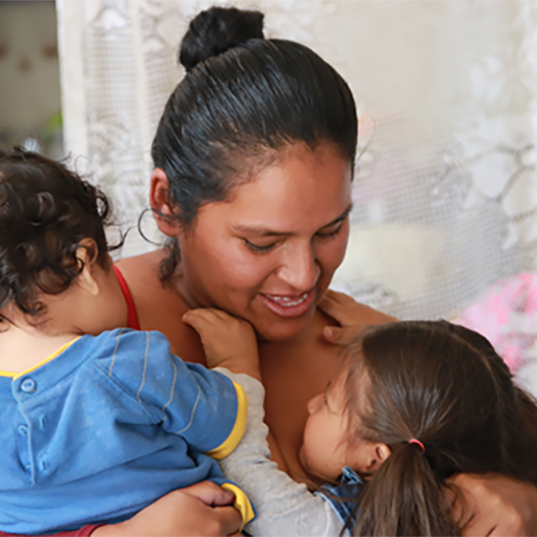 Mother embracing her two young children in Bolivia