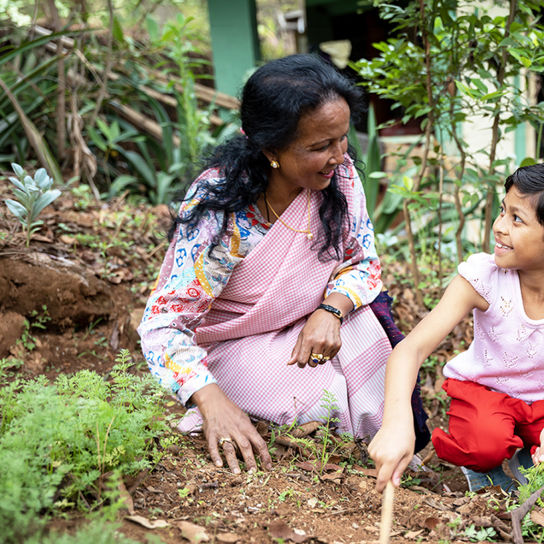 Mother and daughter in India looking at each other lovingly while working in the garden