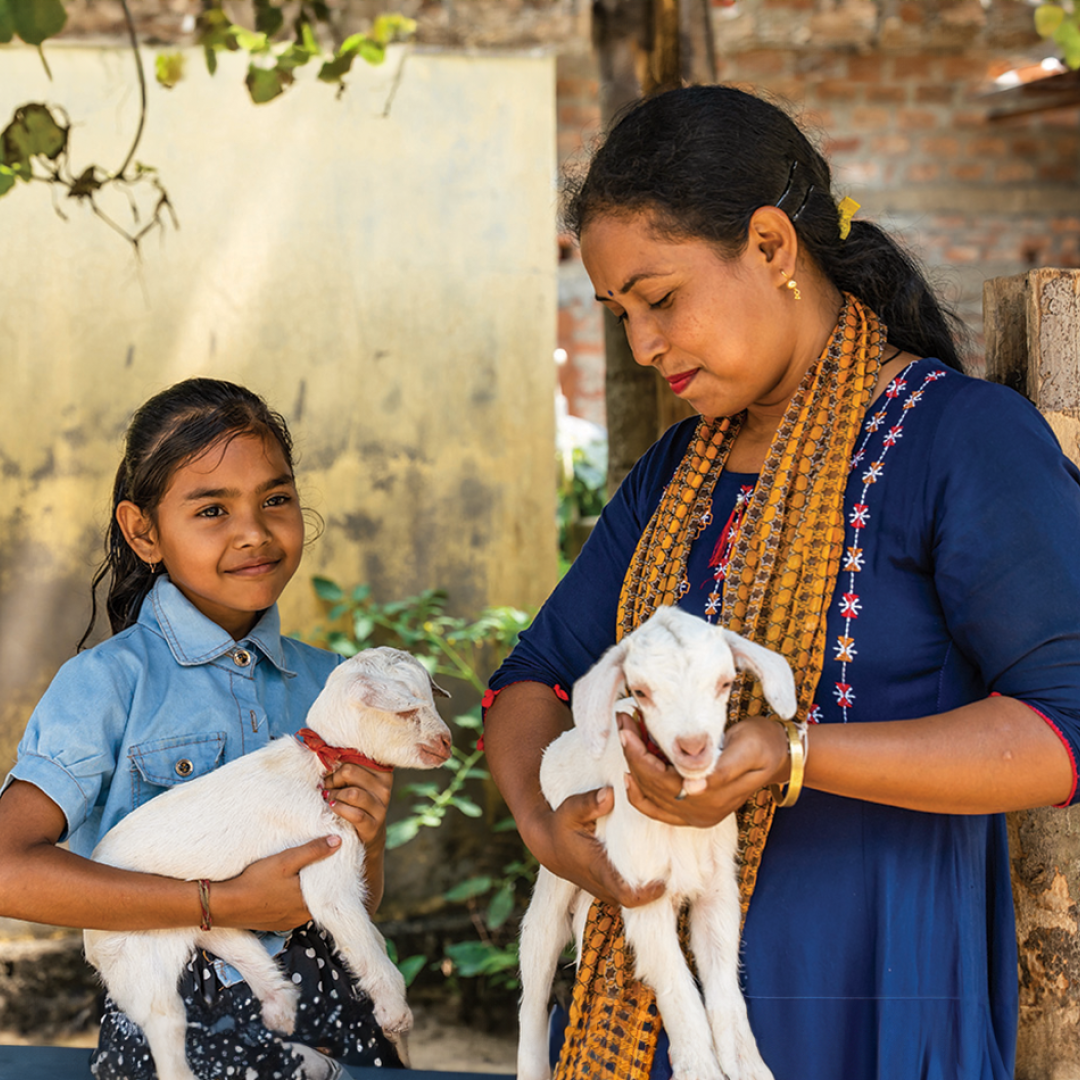 A mother and her daughter holding young goats