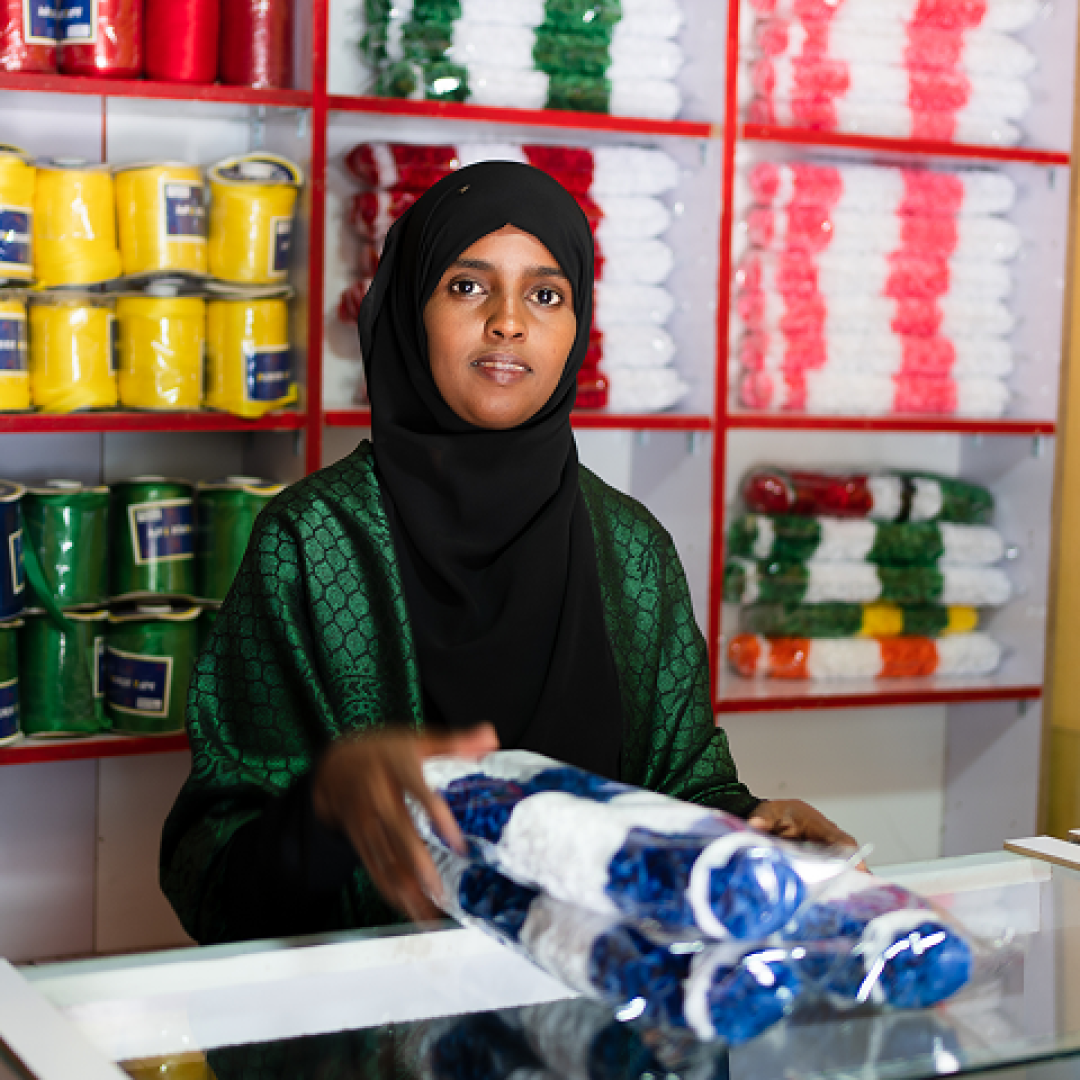Farah stands inside her flower shop in Hargeisa, Somaliland, surrounded by colourful ribbon used to create handcrafted floral arrangements.
