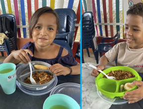 Young boy and girl eating a meal at a child-friendly space in Colombia.