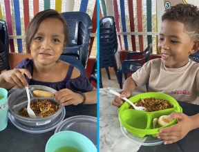 Young boy and girl eating a meal at a child-friendly space in Colombia.