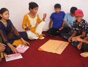 Children sitting together in a children’s club session in Nepal, sharing ideas in a group discussion.