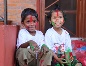 two young children in Nepal with paint on their hands, face and clothes