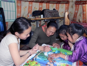 Arban* and her sister working on their studies, with help from mom.