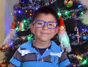 Marco* smiling in front of the Christmas tree