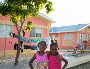 Two smiling SOS children standing in front of their new SOS home.