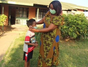 La mère SOS Phoebe aide son plus jeune à mettre un masque de protection
