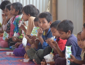 Children eating snack, emergency response program in Bangladesh