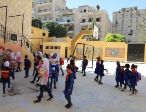 Les enfants à l'extérieur de l'école reconstruite à Alep en Syrie